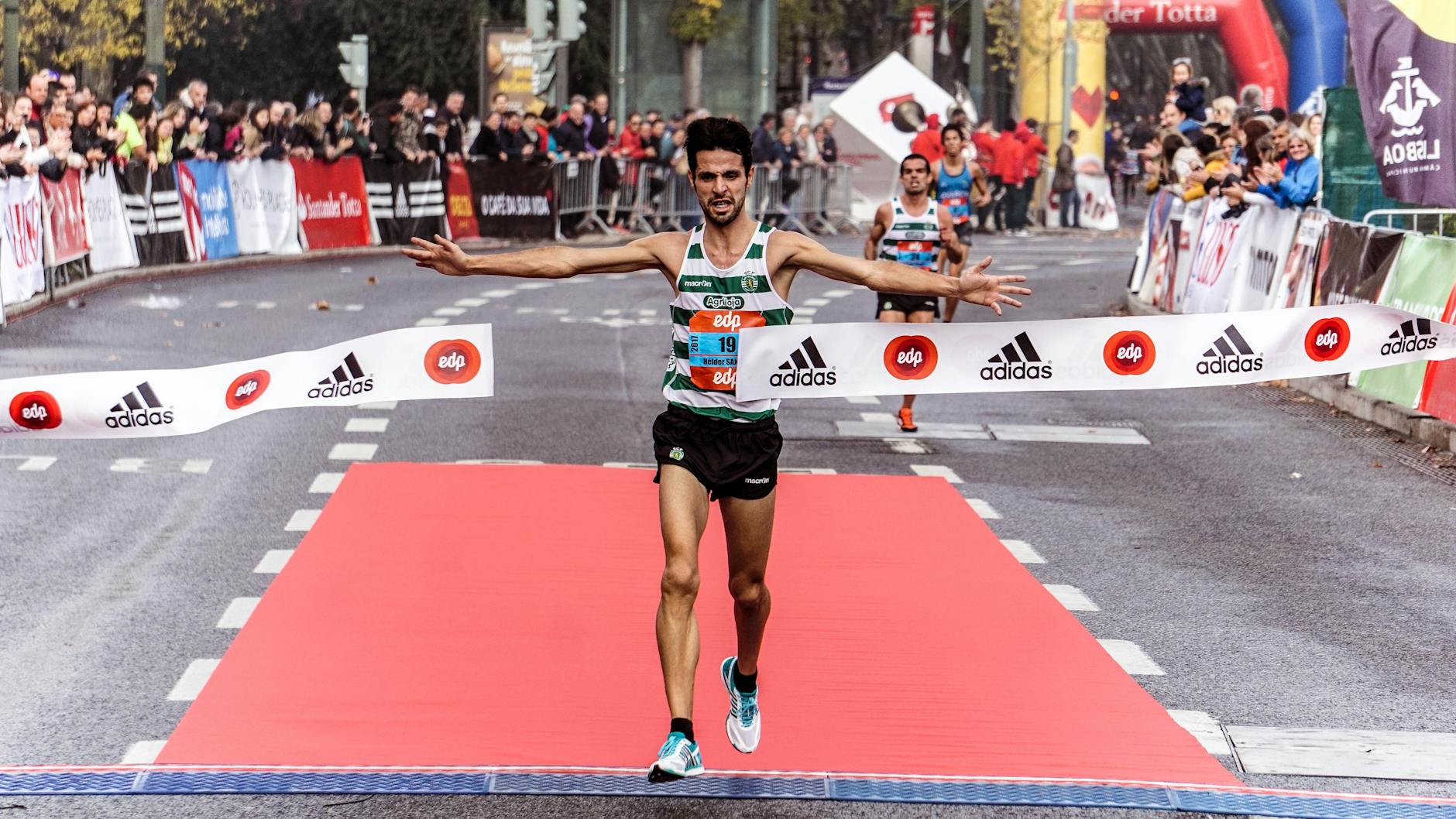 Marathon runner crossing finish line in London, arms raised