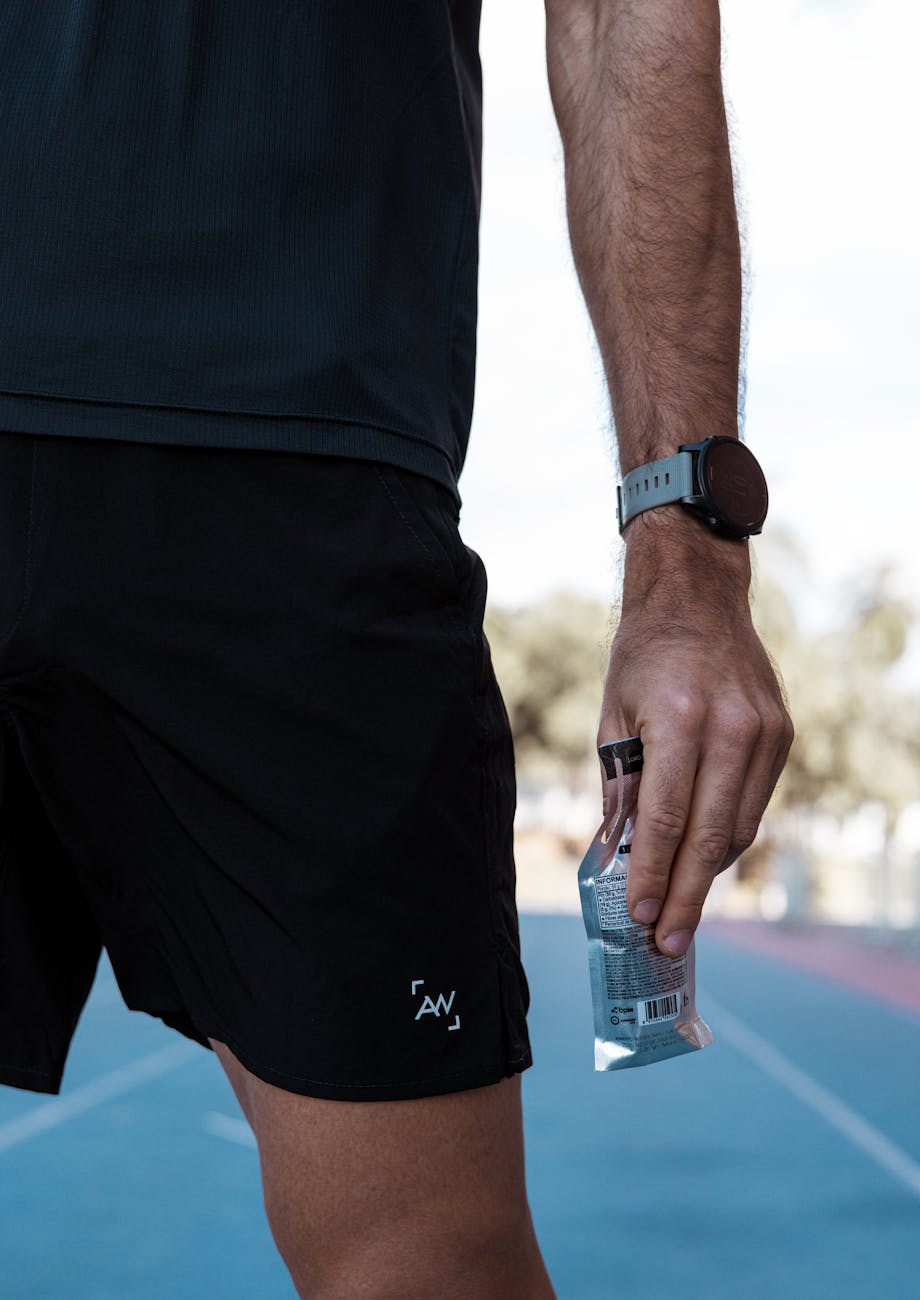 Athlete holding energy gel on outdoor running track, fitness and endurance sports nutrition
