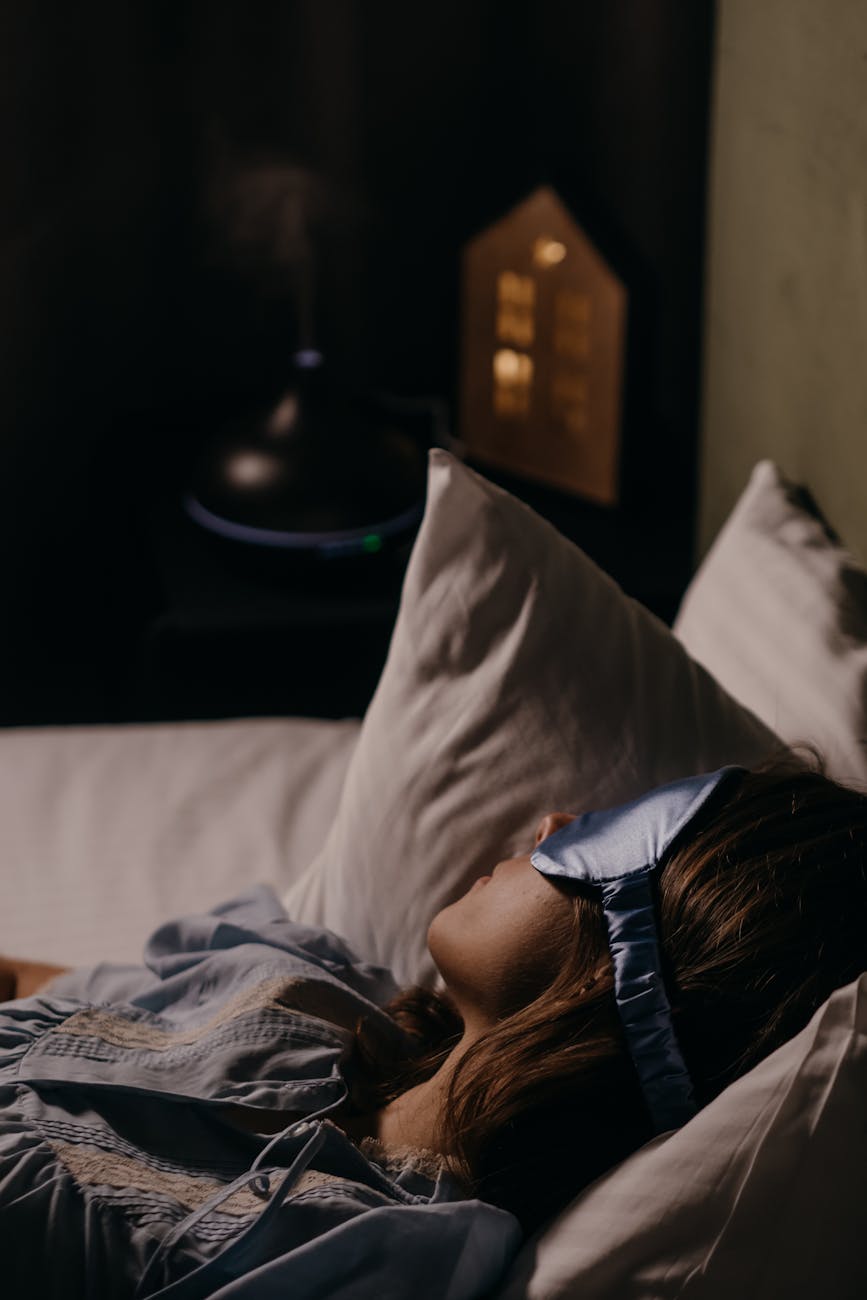 Woman wearing a blue eye mask sleeping comfortably in a cozy bedroom