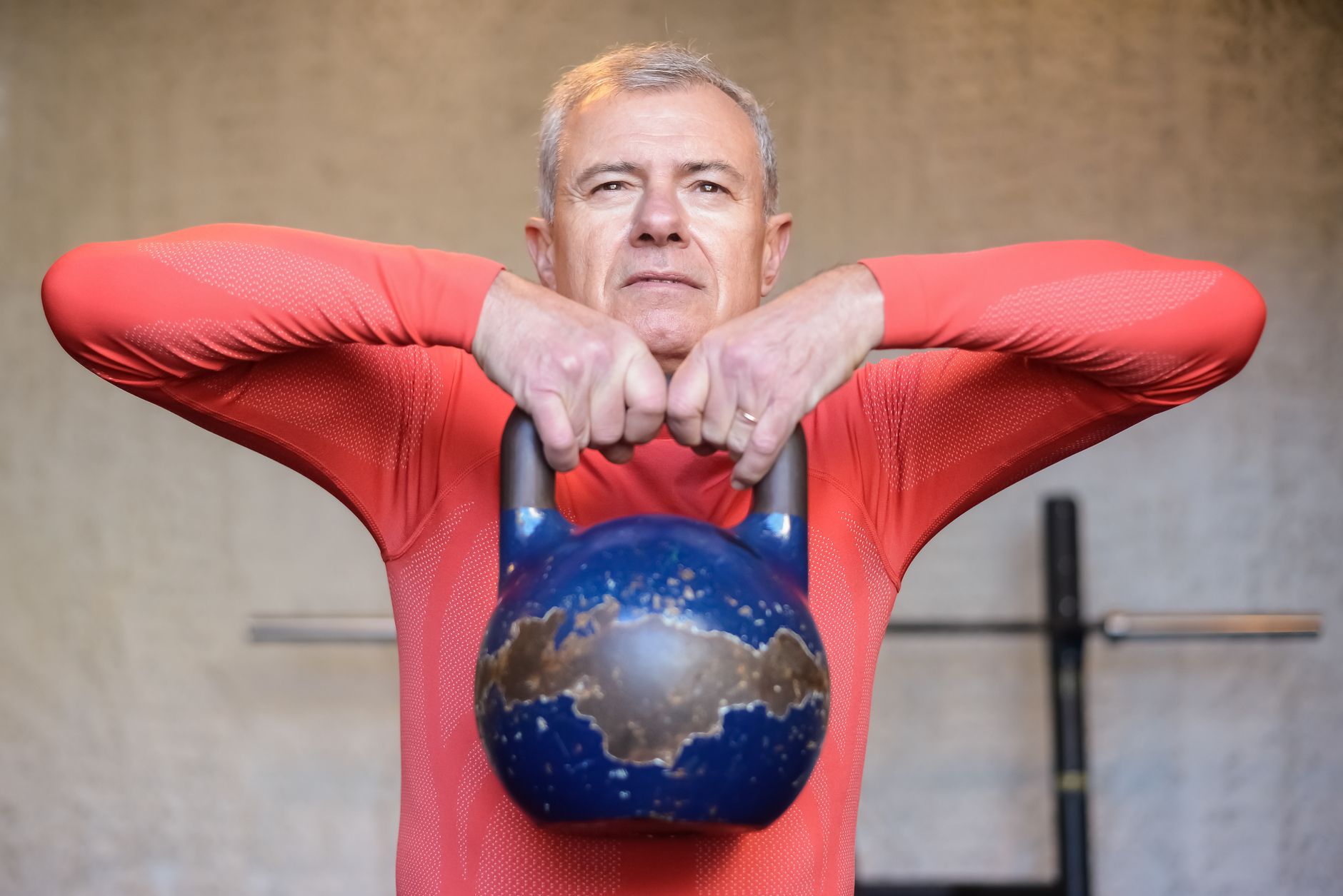 Older man performing a kettlebell exercise indoors